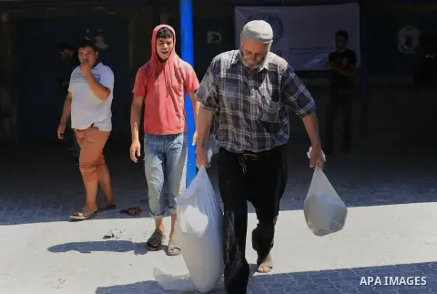 A Palestinian man carries bags of rice and flour at a distribution centre of the United Nations Relief and Works Agency (UNRWA) in Gaza City on August 11, 2014. An Israeli delegation arrived in Cairo for indirect negotia...