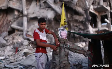 A Palestinian places a poster of late leader Yasser Arafat at a tent outside houses, which witnesses said were destroyed in an Israeli offensive, during a 72-hour truce in Beit Lahiya town in the northern Gaza Strip Augu...