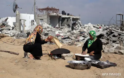 Palestinian women bake bread in front their house, which witnesses said was destroyed during the Israeli offensive, during a 72-hour truce at al-Fakhari district in the east of Khan Younis town southern the Gaza Strip on...