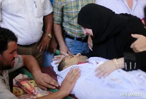 Relatives and friends mourn over the body of Ali Shehada Abu Afash, translator working with The Associated Press, during his funeral in Gaza City on August 13, 2014. Afash was killed in an ordnance explosion in the Gaza...