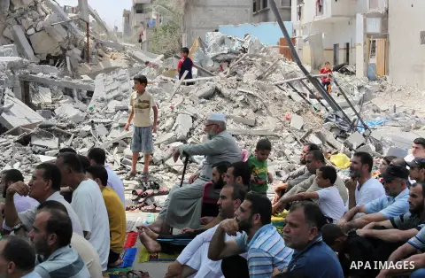 Palestinian worshipers perform Friday prayers next to the remains of a mosque which witnesses said was destroyed by an Israel air strike during the offensive, on the second day of a five-day ceasefire in Nuseirat refugee...