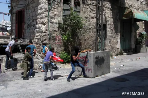 Palestinian protesters throw stones towards Israeli security forces during clashes following a demonstration to support people in Gaza and Palestinian negotiators in Cairo, Egypt, in West Bank city of Hebron on Friday, A...