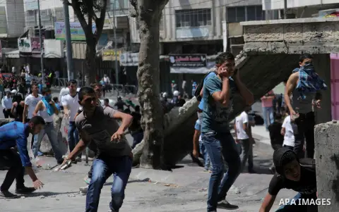 Palestinian protesters throw stones towards Israeli security forces during clashes following a demonstration to support people in Gaza and Palestinian negotiators in Cairo, Egypt, in West Bank city of Hebron on Friday, A...