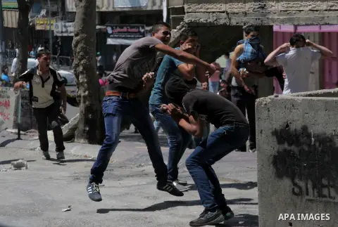 Palestinian protesters throw stones towards Israeli security forces during clashes following a demonstration to support people in Gaza and Palestinian negotiators in Cairo, Egypt, in West Bank city of Hebron on Friday, A...