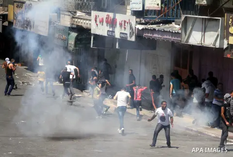 Palestinian protesters throw stones towards Israeli security forces during clashes following a demonstration to support people in Gaza and Palestinian negotiators in Cairo, Egypt, in West Bank city of Hebron on Friday, A...