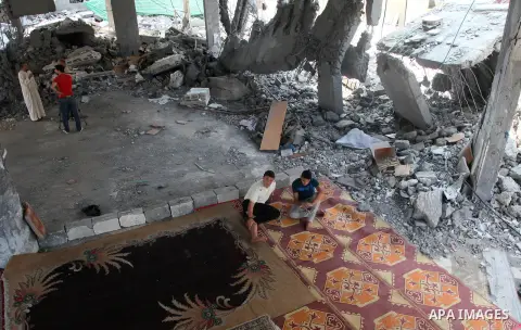 Palestinians sit at a mosque which witnesses said was destroyed by an Israel air strike during the offensive, on the second day of a five-day ceasefire, in Gaza city on August 15, 2014. Israel and Palestinians are observ...