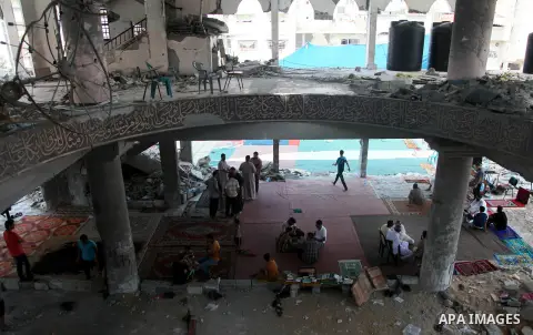 Palestinians sit at a mosque which witnesses said was destroyed by an Israel air strike during the offensive, on the second day of a five-day ceasefire, in Gaza city on August 15, 2014. Israel and Palestinians are observ...