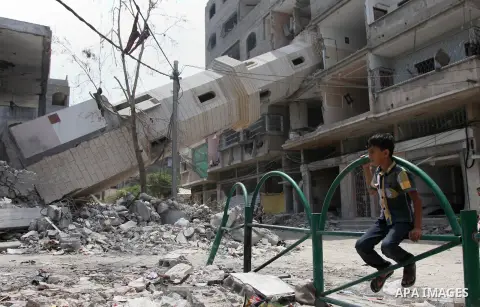 A Palestinian boy sits in front of the remains of a mosque which witnesses said was destroyed by an Israel air strike during the offensive, on the second day of a five-day ceasefire, in Gaza city on August 15, 2014. Isra...