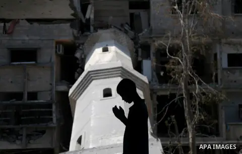A Palestinian boy prays at a mosque which witnesses said was destroyed by an Israel air strike during the offensive, on the second day of a five-day ceasefire, in Gaza city on August 15, 2014. Israel and Palestinians are...