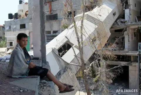 A Palestinian boy sits at a mosque which witnesses said was destroyed by an Israel air strike during the offensive, on the second day of a five-day ceasefire, in Gaza city on August 15, 2014. Israel and Palestinians are...
