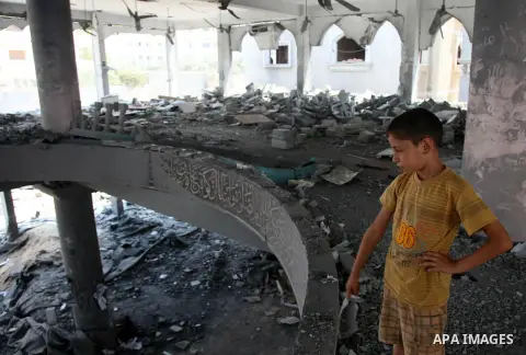 A Palestinian boy looks at the damage at a mosque which witnesses said was destroyed by an Israel air strike during the offensive, on the second day of a five-day ceasefire, in Gaza city on August 15, 2014. Israel and Pa...