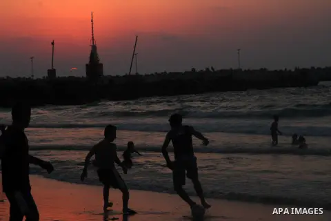 Palestinian youths play football during the sunset at the beach of Gaza City August 14, 2014. Israel and Palestinians are observing a five-day cease-fire which began at midnight Wednesday, in an attempt to allow talks be...