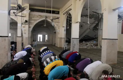 Palestinian worshipers perform Friday prayers next to the remains of a mosque which witnesses said was destroyed by an Israel air strike during the offensive, on the second day of a five-day ceasefire in Gaza City August...