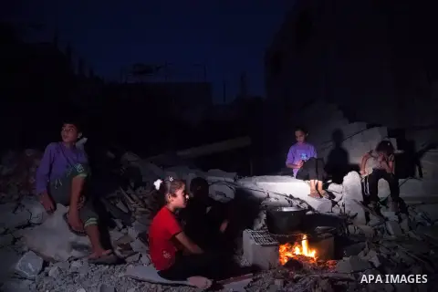 Palestinian family sits around the fire near the rubble of thier house destroyed during fighting between Hamas and Israel in the town of Beit Hanoun, in the northern Gaza Strip, on August 16, 2014. The United Nations est...