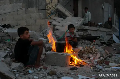 Palestinian family sits around the fire near the rubble of thier house destroyed during fighting between Hamas and Israel in the town of Beit Hanoun, in the northern Gaza Strip, on August 16, 2014. The United Nations est...