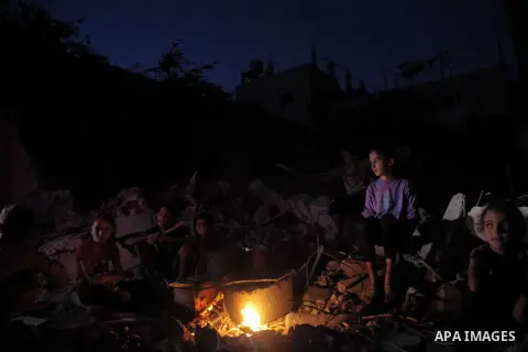 Palestinian family sits around the fire near the rubble of thier house destroyed during fighting between Hamas and Israel in the town of Beit Hanoun, in the northern Gaza Strip, on August 16, 2014. The United Nations est...
