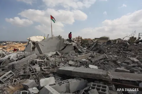 A Palestinian flag flutters as a boy walks amongst the ruins of a house which witnesses said was destroyed by an Israeli air strike during the offensive in Johr El-Deek village near the central Gaza Strip August 17, 2014...