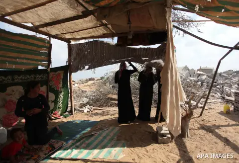Palestinians sit in their house which witnesses said was damaged during the Israeli air offensive in Johr El-Deek village near the central Gaza Strip August 17, 2014. Prime Minister Benjamin Netanyahu said on Sunday any...