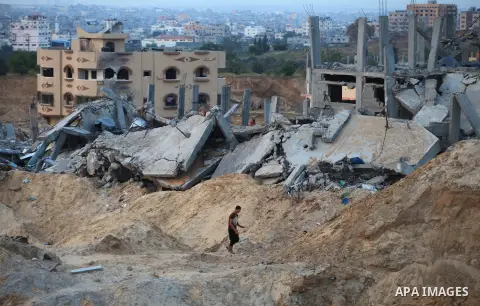 Palestinians walks past buildings destroyed during fighting between Hamas militants and Israel in the Al-Shaaf neighbourhood, in Gaza City, on August 18, 2014.Prime Minister Benjamin Netanyahu warned that Israel will hit...