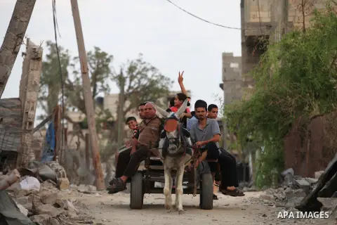 A group of Palestinians carry some of their belonging as they walk past a destroyed home, back to a UN school where many displaced Palestinians are taking refuge, in the Shejaiya neighborhood of Gaza City, on August 18,...