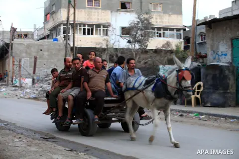 A group of Palestinians carry some of their belonging as they walk past a destroyed home, back to a UN school where many displaced Palestinians are taking refuge, in the Shejaiya neighborhood of Gaza City, on August 18,...