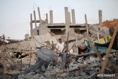 Palestinians walks past buildings destroyed during fighting between Hamas militants and Israel in the Al-Shaaf neighbourhood, in Gaza City, on August 18, 2014.Prime Minister Benjamin Netanyahu warned that Israel will hit...