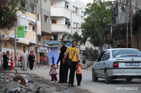 A group of Palestinians carry some of their belonging as they walk past a destroyed home, back to a UN school where many displaced Palestinians are taking refuge, in the Shejaiya neighborhood of Gaza City, on August 18,...