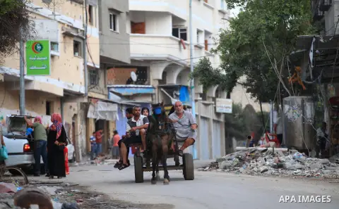 A group of Palestinians carry some of their belonging as they walk past a destroyed home, back to a UN school where many displaced Palestinians are taking refuge, in the Shejaiya neighborhood of Gaza City, on August 18,...