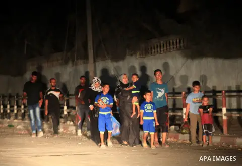 A group of Palestinians carry some of their belonging as they walk past a destroyed home, back to a UN school where many displaced Palestinians are taking refuge, in the Shejaiya neighborhood of Gaza City, on August 18,...