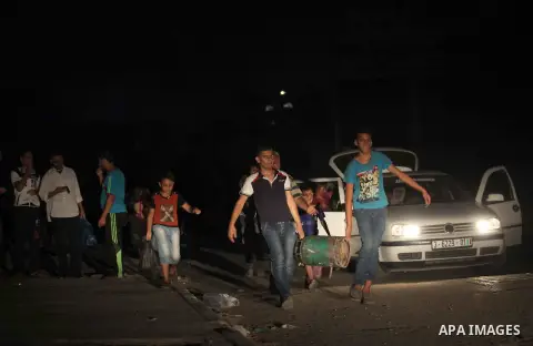 A group of Palestinians carry some of their belonging as they walk past a destroyed home, back to a UN school where many displaced Palestinians are taking refuge, in the Shejaiya neighborhood of Gaza City, on August 18,...