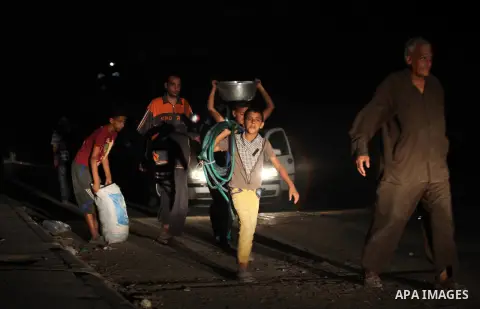 A group of Palestinians carry some of their belonging as they walk past a destroyed home, back to a UN school where many displaced Palestinians are taking refuge, in the Shejaiya neighborhood of Gaza City, on August 18,...