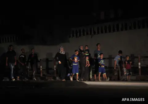 A group of Palestinians carry some of their belonging as they walk past a destroyed home, back to a UN school where many displaced Palestinians are taking refuge, in the Shejaiya neighborhood of Gaza City, on August 18,...