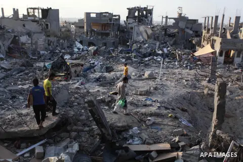 Palestinians walks past buildings destroyed during fighting between Hamas militants and Israel in the Al-Shaaf neighbourhood, in Gaza City, on August 18, 2014.Prime Minister Benjamin Netanyahu warned that Israel will hit...