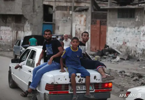 A group of Palestinians carry some of their belonging as they walk past a destroyed home, back to a UN school where many displaced Palestinians are taking refuge, in the Shejaiya neighborhood of Gaza City, on August 18,...