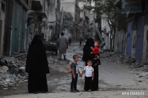 A group of Palestinians carry some of their belonging as they walk past a destroyed home, back to a UN school where many displaced Palestinians are taking refuge, in the Shejaiya neighborhood of Gaza City, on August 18,...