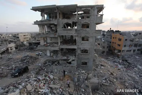 Palestinians walks past buildings destroyed during fighting between Hamas militants and Israel in the Al-Shaaf neighbourhood, in Gaza City, on August 18, 2014.Prime Minister Benjamin Netanyahu warned that Israel will hit...