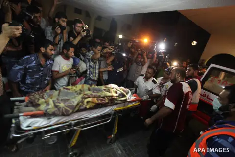 Palestinian medics wheel an death woman on a stretcher into the Shifa hospital following Israeli strikes which hit Gaza City, Tuesday, Aug. 19, 2014.The Israeli air strike killed a young girl and a woman, wounding 16 oth...