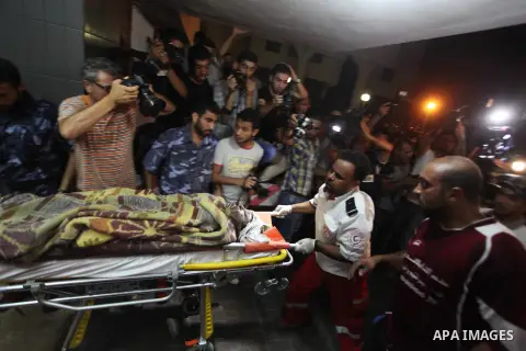 Palestinian medics wheel an death woman on a stretcher into the Shifa hospital following Israeli strikes which hit Gaza City, Tuesday, Aug. 19, 2014.The Israeli air strike killed a young girl and a woman, wounding 16 oth...