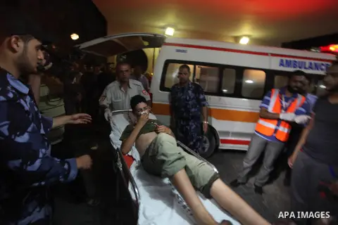 Palestinian medics wheel an injured youth on a stretcher into the Shifa hospital following Israeli strikes which hit Gaza City, Tuesday, Aug. 19, 2014. The Israeli air strike killed a young girl and a woman, wounding 16...