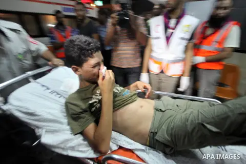Palestinian medics wheel an injured youth on a stretcher into the Shifa hospital following Israeli strikes which hit Gaza City, Tuesday, Aug. 19, 2014. The Israeli air strike killed a young girl and a woman, wounding 16...