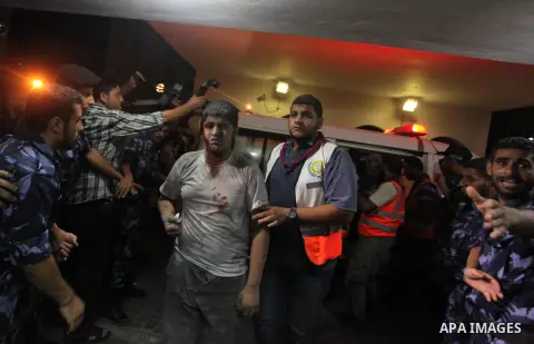 Palestinian medics wheel an injured youth on a stretcher into the Shifa hospital following Israeli strikes which hit Gaza City, Tuesday, Aug. 19, 2014. The Israeli air strike killed a young girl and a woman, wounding 16...