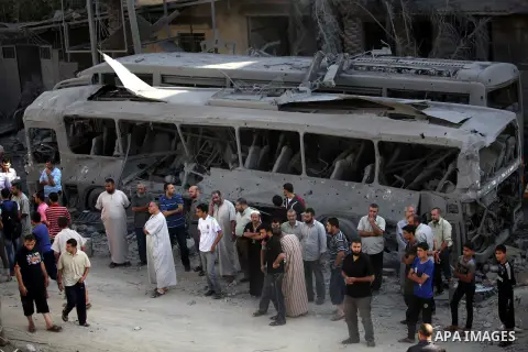 Palestinians stand in front of a bus that witnesses said was destroyed during an Israeli airstrike in Gaza City August 20, 2014. Hamas militants in the Gaza Strip fired rockets at Israel for a second day on Wednesday aft...