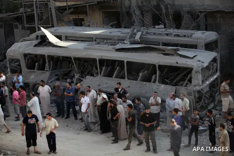 Palestinians stand in front of a bus that witnesses said was destroyed during an Israeli airstrike in Gaza City August 20, 2014. Hamas militants in the Gaza Strip fired rockets at Israel for a second day on Wednesday aft...