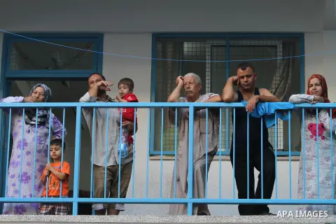 Palestinians watch children participating in recreational events at a UN school, that shelters hundreds of families after fighting between Israel and Hamas broke out July 8, during a morning activity on the day that scho...