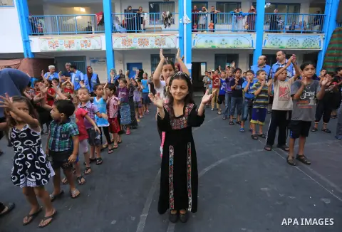 Palestinian children line up in the courtyard of a UN school, that shelters hundreds of families after fighting between Israel and Hamas broke out July 8, during a morning activity on the day that schools across Gaza wer...