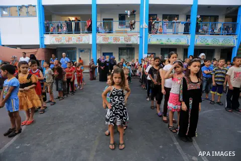 Palestinian children line up in the courtyard of a UN school, that shelters hundreds of families after fighting between Israel and Hamas broke out July 8, during a morning activity on the day that schools across Gaza wer...