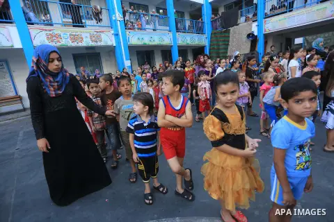 Palestinian children line up in the courtyard of a UN school, that shelters hundreds of families after fighting between Israel and Hamas broke out July 8, during a morning activity on the day that schools across Gaza wer...