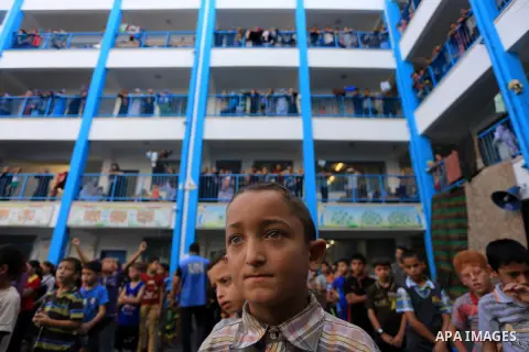 Palestinian children line up in the courtyard of a UN school, that shelters hundreds of families after fighting between Israel and Hamas broke out July 8, during a morning activity on the day that schools across Gaza wer...