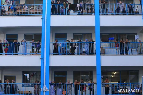 Palestinians watch children participating in recreational events at a UN school, that shelters hundreds of families after fighting between Israel and Hamas broke out July 8, during a morning activity on the day that scho...