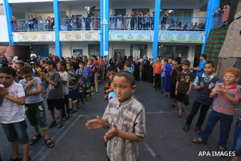 Palestinian children line up in the courtyard of a UN school, that shelters hundreds of families after fighting between Israel and Hamas broke out July 8, during a morning activity on the day that schools across Gaza wer...